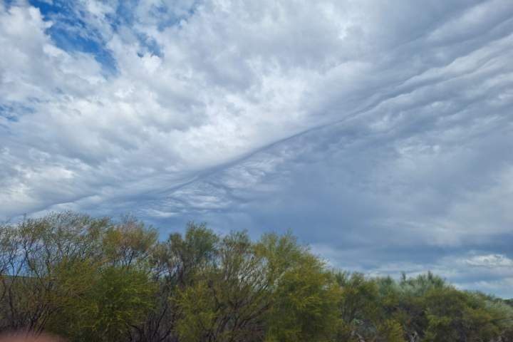 a person standing in front of a cloudy blue sky